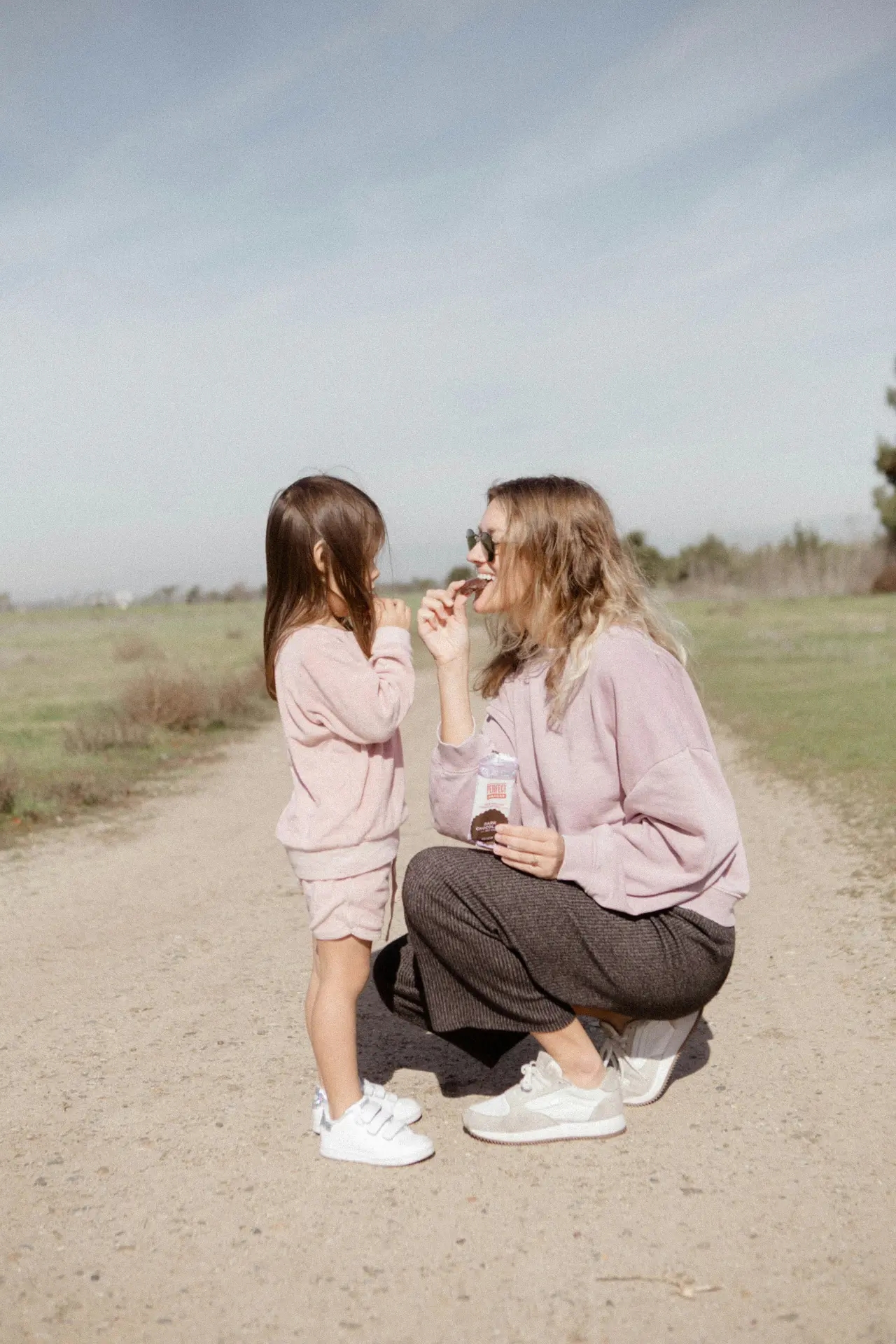 Mamá jugando con su hija en un camino al aire libre